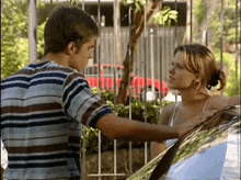 a man in a striped shirt is touching a woman 's shoulder