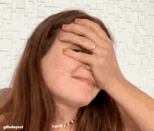 a woman with a ring on her finger covering her face with her hand