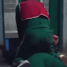 a man in a green suit is kneeling down on another man 's lap .