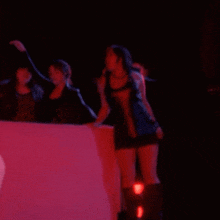 a woman singing into a microphone in a dark room with red lights behind her
