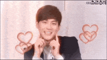 a young man is making a heart shape with his hands and smiling .