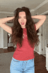 a woman wearing a red shirt that says ' abercrombie & fitch ' on it is sticking her tongue out