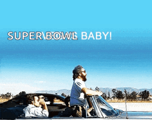 a man driving a car with the words super bowl baby on the bottom