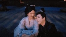 a man and a woman are sitting next to each other and hugging each other .