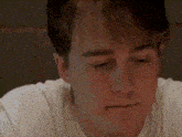 a close up of a man 's face with his eyes closed and a white shirt on