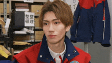 a young man wearing a red and blue jacket has a badge on his jacket that says ' a ' on it