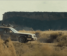 a sheriff 's car is driving through a grassy field