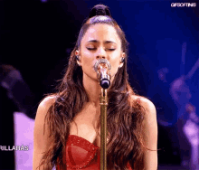 a woman in a red dress is singing into a microphone with gifsoftinis written on the bottom of the screen