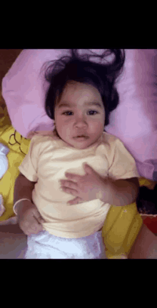 a baby in a yellow shirt is laying down