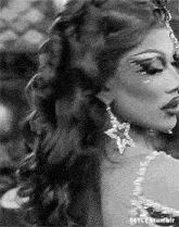a black and white photo of a woman wearing earrings and a crown .