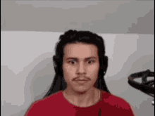 a man wearing headphones and a red shirt is looking at the camera