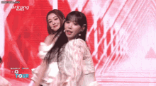 two women are dancing on a stage in front of a screen that says korea