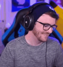 a man wearing headphones and glasses is smiling while sitting in a chair .