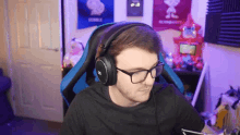 a man wearing glasses and headphones is sitting in a chair .