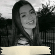 a black and white photo of a girl smiling with a banner in the foreground