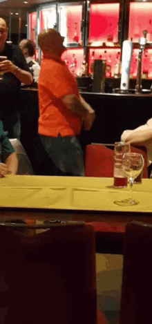 a man in an orange shirt is dancing in a restaurant