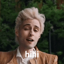a man with blonde hair is making a funny face and the word hini is on his face .