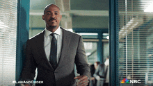 a man in a suit and tie is standing in a doorway with the nbc logo on the bottom