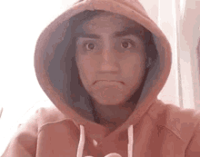 a person wearing a pink hoodie is making a funny face .