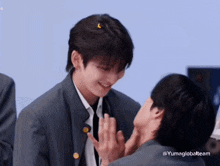 a man in a suit is touching another man 's face