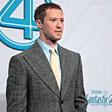 a man in a suit is standing in front of a fantastic 4 logo