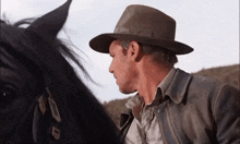 a man wearing a hat stands next to a horse