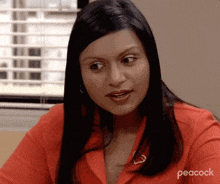 a woman in a red shirt is sitting in front of a window in an office .