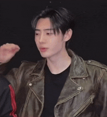 a young man wearing a brown leather jacket and black shirt