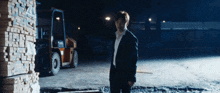a man in a suit stands in front of a forklift that says toyota
