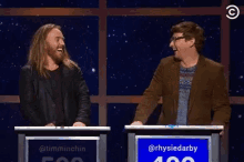a man and a woman are giving each other a high five in front of a sign that says rhysiedarby