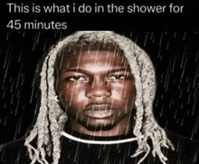 a man with dreadlocks is taking a shower with rain falling on his head .
