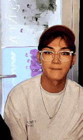 a young man wearing glasses and a white shirt with the word smile on the back