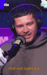 a man wearing headphones is talking into a microphone and the words that was super gay are next to him