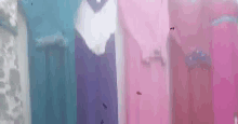 a row of pink , purple , and blue dresses are hanging on a rack .