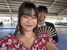 a boy and a girl are posing for a picture with a fan in front of them