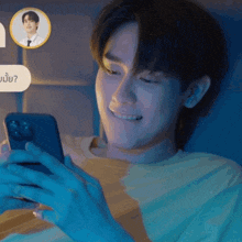 a man in a yellow shirt is smiling while looking at a cell phone