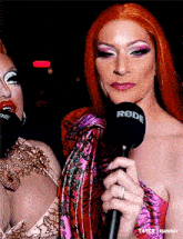 a woman holding a rode microphone next to another woman