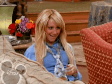 a woman is sitting on a couch wearing a blue shirt and tie .
