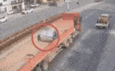 a truck is driving down a road with a red tarp on the back .