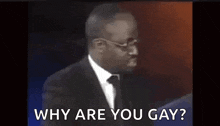 a man in a suit and tie is talking about why are you gay .