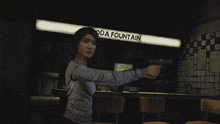 a woman is pointing a gun in front of a soda fountain