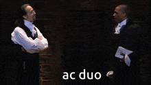 two men are standing next to each other and the word ac duo is on the bottom