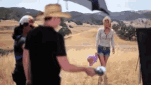 a man in a straw hat stands in a field with a woman