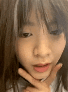a close up of a girl 's face with her hand on her chin and making a funny face .