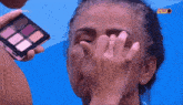 a woman is applying makeup on a blue background with globoplay in the upper left corner