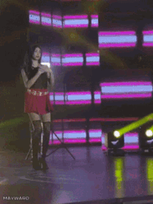 a woman in a red skirt is dancing on a stage with mayward written on the bottom right corner