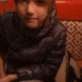 a person is sitting in a chair with their arms crossed and a black jacket on