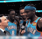 a group of thunder players are talking to a man in a suit