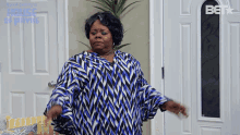 a woman in a blue and white shirt is standing in front of a door that says bet on it