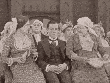 a man in a suit sits in front of a crowd of people